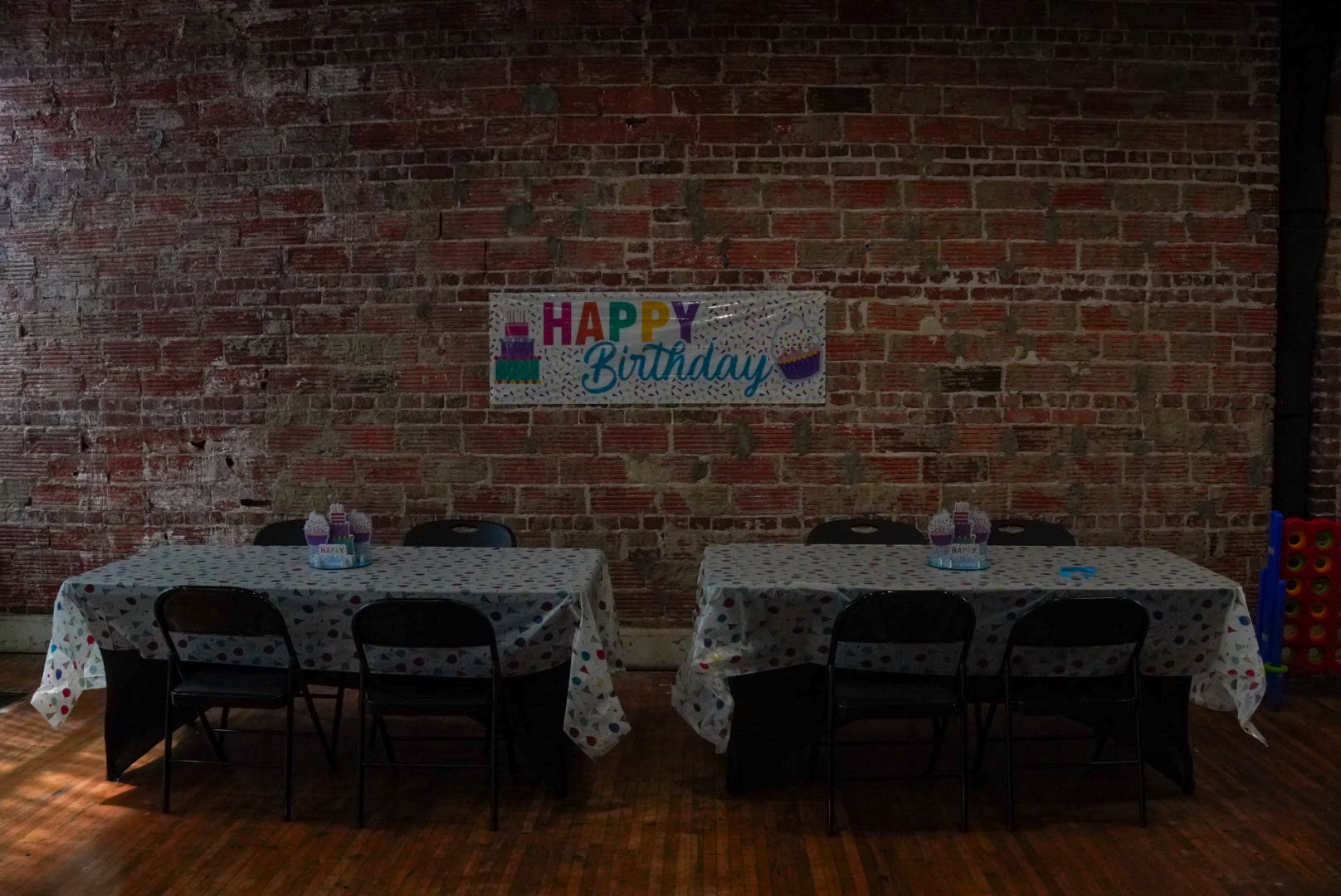 Birthday party setup with Happy Birthday banner against exposed brick wall
