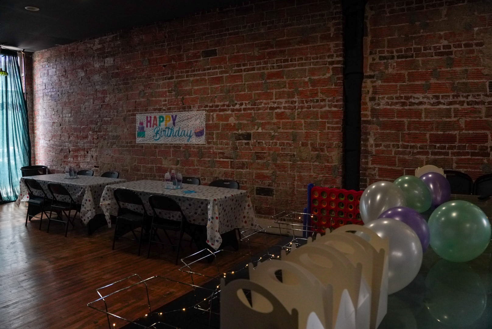 Event space with birthday banner, balloons, tables, and party games