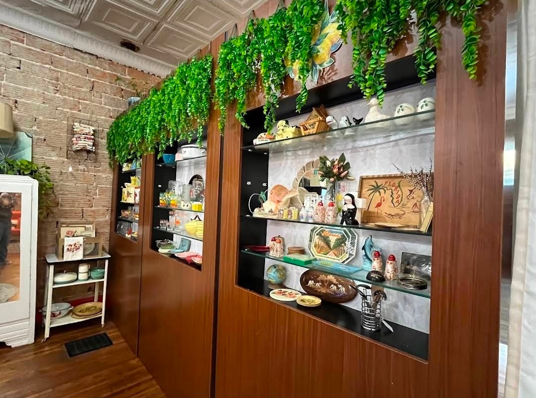 Lemonade Gifts vintage collectibles shelves with hanging greenery